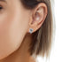 Close-up of a person wearing Dolphin Charm Stud Earrings crafted from white gold and embellished with dazzling zirconia stones. The person's skin is smooth, and their hair is shoulder-length and brown.